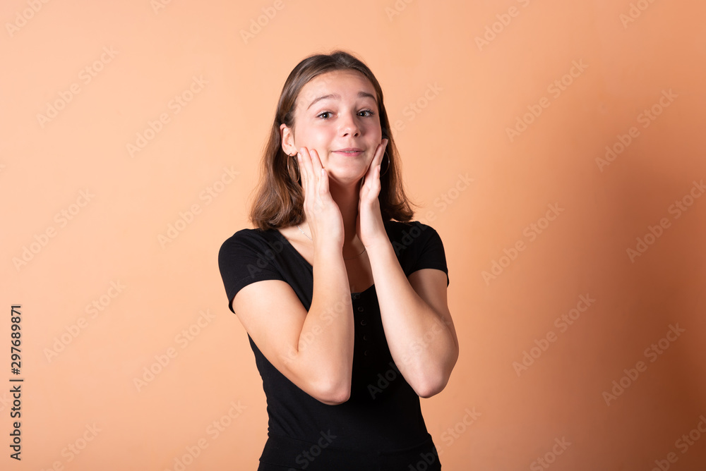 The girl is worried and holds on to her head, on a light orange background. The girl is worried and holds on to her head, on a light orange background.