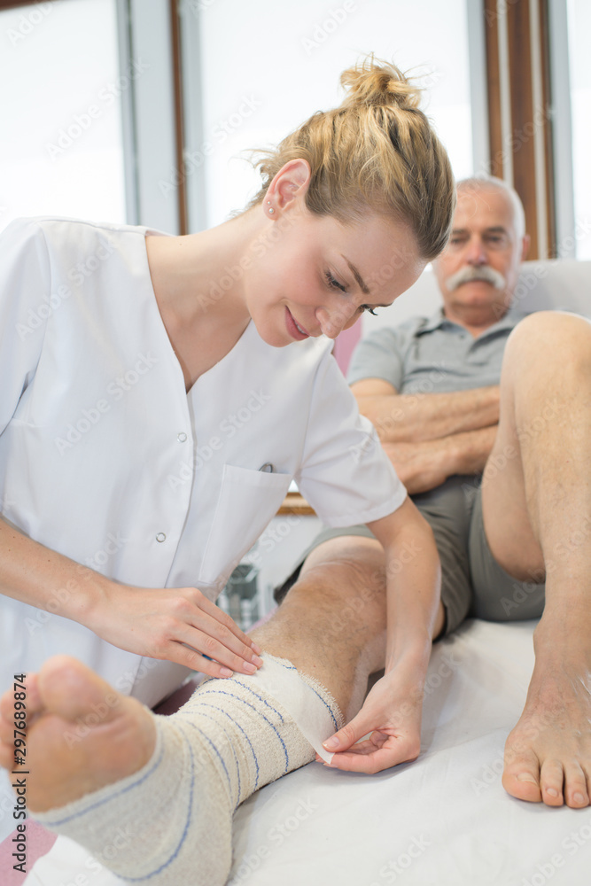Fototapeta premium beautiful female medical bandaging senior leg