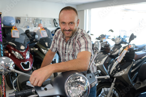 glad motorcyclist sitting on the motorbike in the store