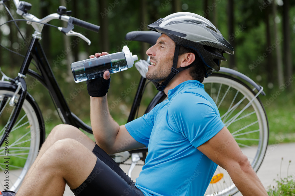 Naklejka premium handsome man riding bike and drinking water resting