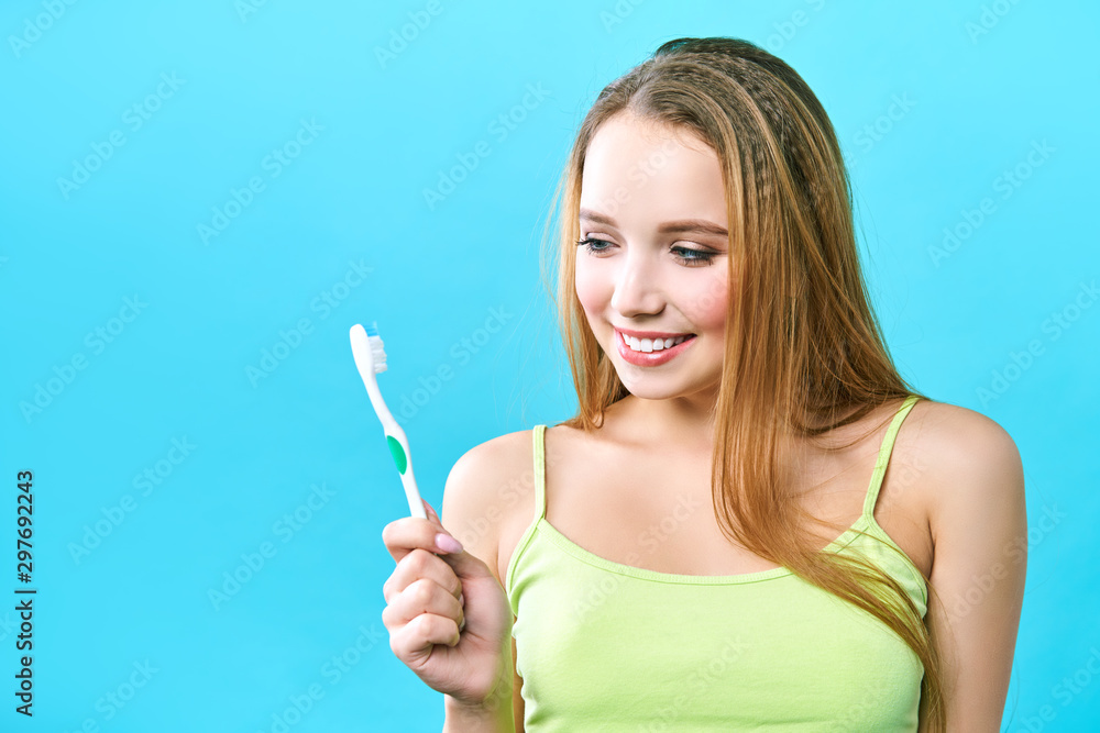 Young beautiful woman is engaged in cleaning teeth. Beautiful smile healthy white teeth. A girl holds a toothbrush. The concept of oral hygiene. Promotional image for a stomatology, dental clinic Young beautiful woman is engaged in cleaning teeth. Beautiful smile healthy white teeth. A girl holds a toothbrush. The concept of oral hygiene. Promotional image for a stomatology, dental clinic