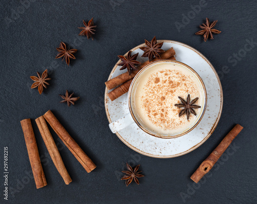Indian Masala chai tea. Traditional Indian hot drink with milk and spices on dark stone table background. Top view, flat lay