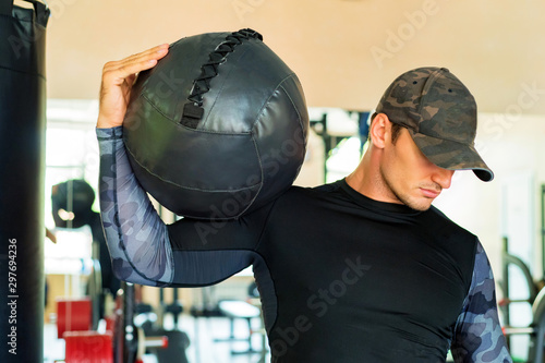 Athlete is holding black exercise ball in gym