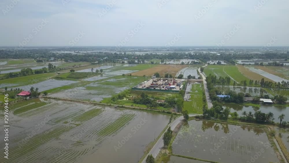 Oil and gas a land rig, onshore drilling rig, in the middle of a rice field aerial view from a drone Oil and gas a land rig, onshore drilling rig, in the middle of a rice field aerial view from a drone