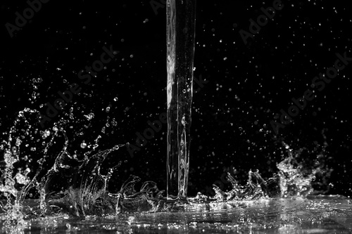 Water splash on black background. Jet and drops of clear liquid. Pouring transparent water
