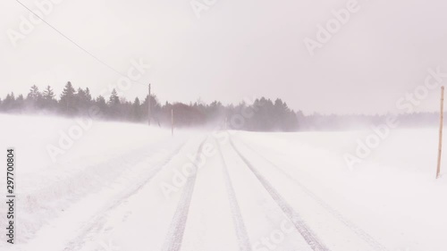 Blizzard with Snow Drifting above Road with Car Track Tracks