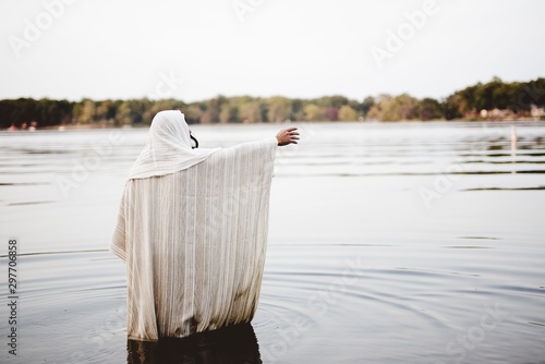 Photography Person wearing a biblical robe standing in the water with a hand up shot from be