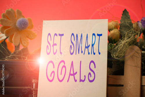 Handwriting text Set Smart Goals. Conceptual photo giving criteria to guide in the setting of objectives Flowers and writing equipments plus plain sheet above textured backdrop photo