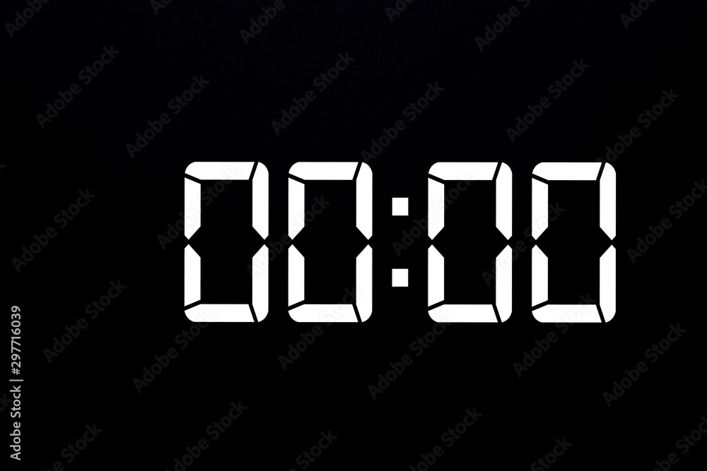 Showing time 00:00 on white led digital clock isolated black background