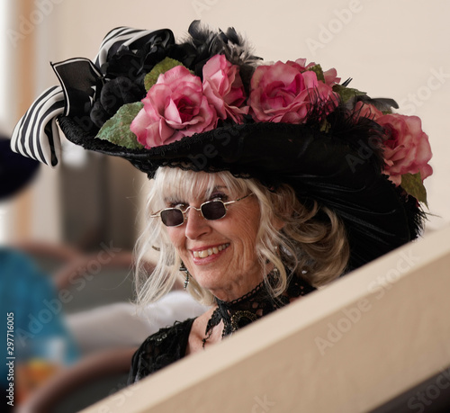 Portrait of an attractive senior in period dress, including a very elaborate feathered and flowered hat.