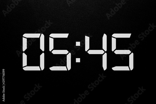 Showing time 05:45 on white led digital clock isolated black background