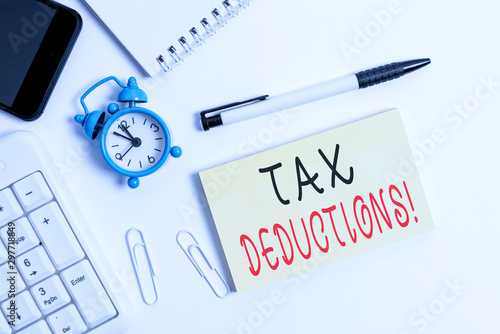 Text sign showing Tax Deductions. Business photo text reduction income that is able to be taxed of expenses Flat lay above computer mobile phone clock pencil and copy space note paper