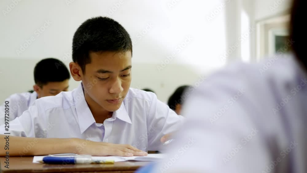 Asian high school students in white uniform are doing examinations. Asian high school students in white uniform are doing examinations.