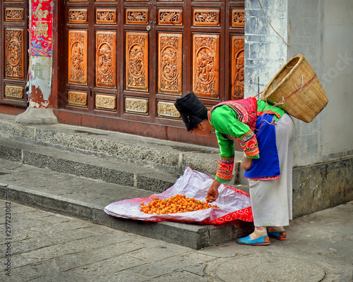 Photography Bai woman selling loquats in the streets of Dali ancient city, Yunnan province, China