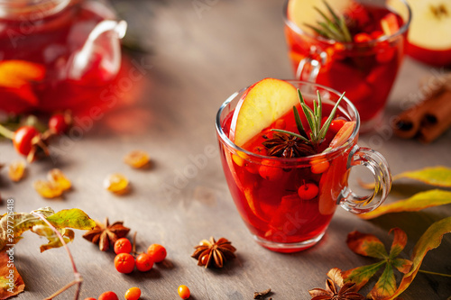 Mulled wine with fruits and spices in glass on a wooden background. Traditional hot drink at Autumn time
