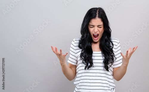Young woman feeling stressed on a gray background