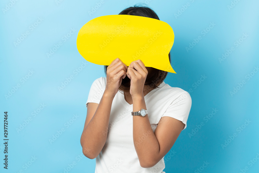 Portrait of young girl holding a empty yellow speech bubble isolated on blue background Portrait of young girl holding a empty yellow speech bubble isolated on blue background