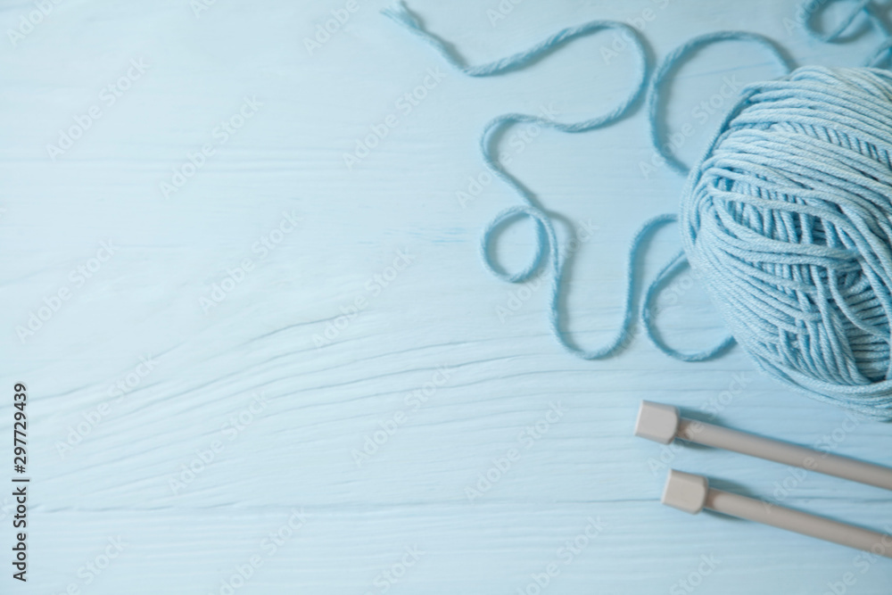 Yarn of green, turquoise, aquamarine and blue colors. White wood background. Knitting needles and crochet hooks. Scissors. Blue background. Yarn of green, turquoise, aquamarine and blue colors. White wood background. Knitting needles and crochet hooks. Scissors. Blue background.