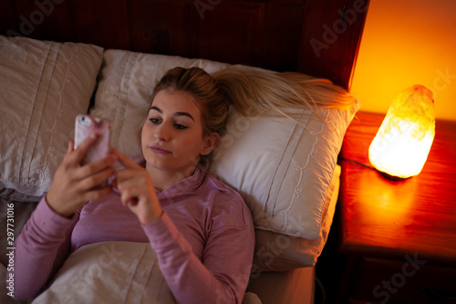 Smart phone person scrolling in bed salt lamp photo