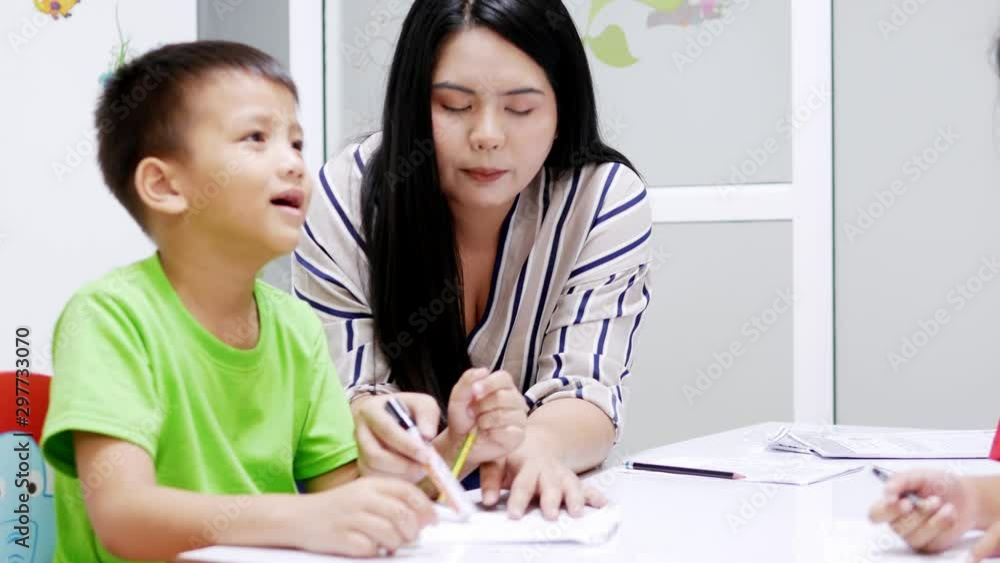 Asian elementary school children are studying in the classroom with an Asian female teacher. Asian elementary school children are studying in the classroom with an Asian female teacher.