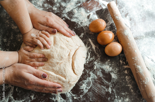 Fotografia Hands of mother and son kneading a dough together