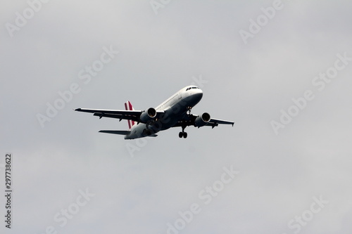 Commercial passenger airplane climbing after take off from local airport surrounded with clear grey sky on warm summer day