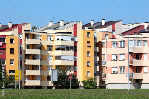 Restored five storey attached apartment buildings with new colorful facades and multiple balconies surrounded with grass and clear blue sky in background