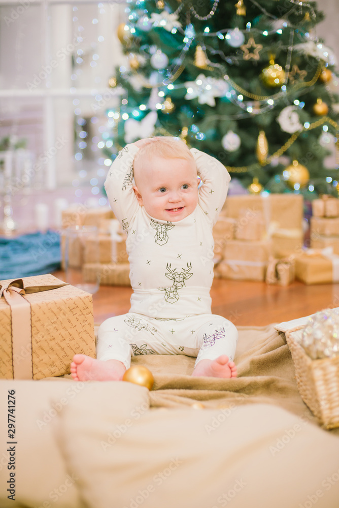 Little toddler boy at home at the Christmas tree with gifts and toys. Christmas mood Little toddler boy at home at the Christmas tree with gifts and toys. Christmas mood