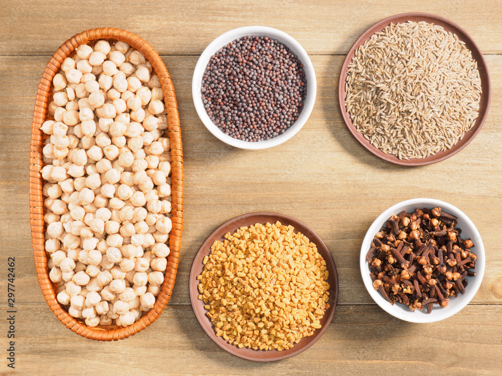 Mung bean, mustard seeds, fenugreek, cumin, cloves on brown wooden background. Indian cuisine, ayurveda, naturopathy, modern apothecary concept Mung bean, mustard seeds, fenugreek, cumin, cloves on brown wooden background. Indian cuisine, ayurveda, naturopathy, modern apothecary concept