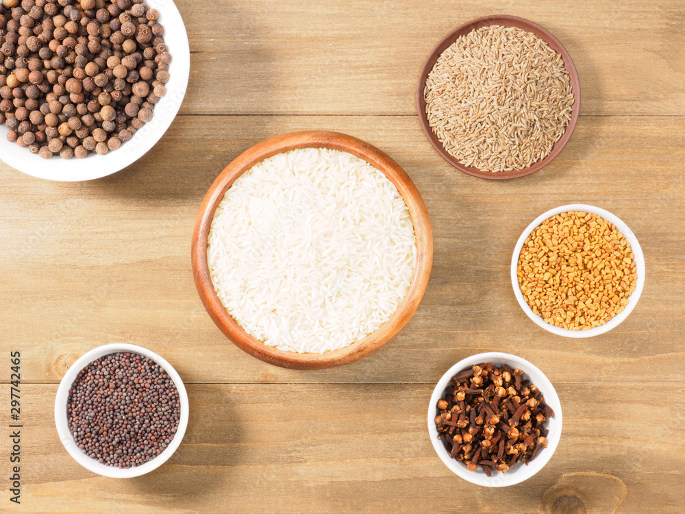 Rice, allspice, mustard seeds, fenugreek, cumin, cloves on brown wooden background. Indian cuisine, ayurveda, naturopathy, modern apothecary concept Rice, allspice, mustard seeds, fenugreek, cumin, cloves on brown wooden background. Indian cuisine, ayurveda, naturopathy, modern apothecary concept