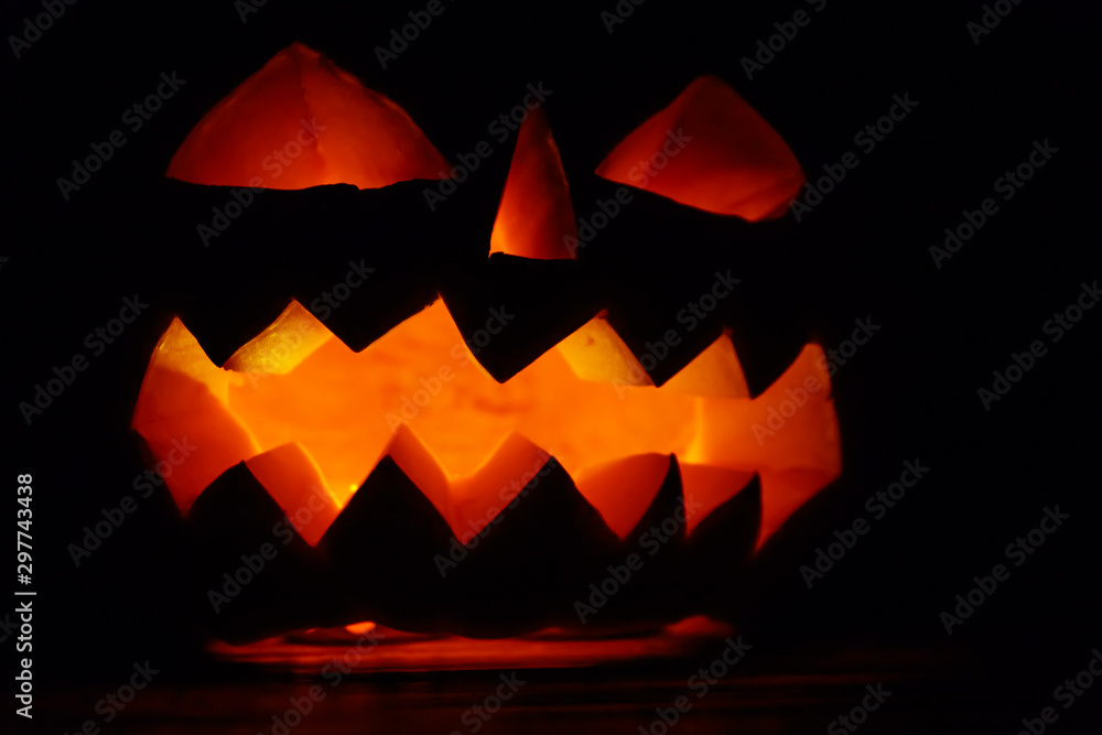 Spooky Halloween pumpkin jack-o-lantern with burning candles on dark background Spooky Halloween pumpkin jack-o-lantern with burning candles on dark background