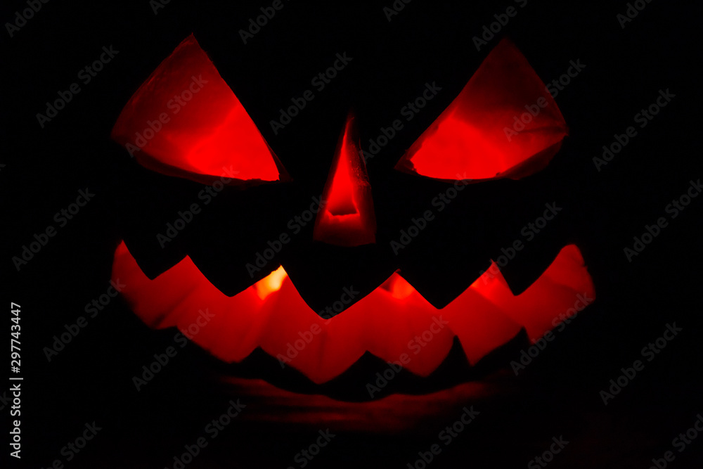 Spooky Halloween pumpkin jack-o-lantern with burning candles on dark background Spooky Halloween pumpkin jack-o-lantern with burning candles on dark background