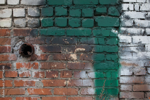 The old cracked wall is made of red brick and with green and white paint. photo