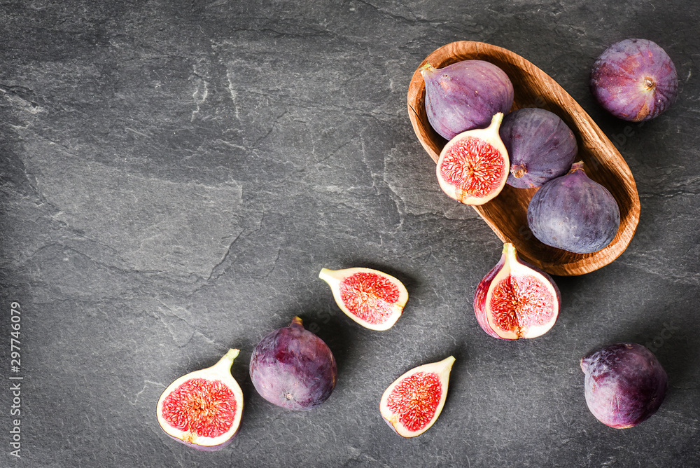 Fresh figs in wooden table on black background. Ripe citrus fig cut fruits on dark stone table from top view. Fresh figs in wooden table on black background. Ripe citrus fig cut fruits on dark stone table from top view.