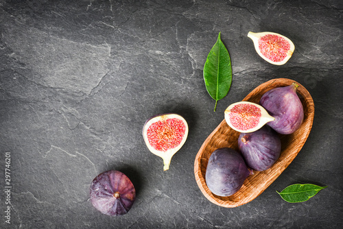 Fresh figs in wooden table on black background. Ripe citrus fig cut fruits on dark stone table from top view.