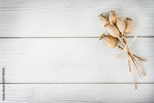 Dried poppy bunch heads on white table from top view. Poppies head bounded on rustic old board. photo