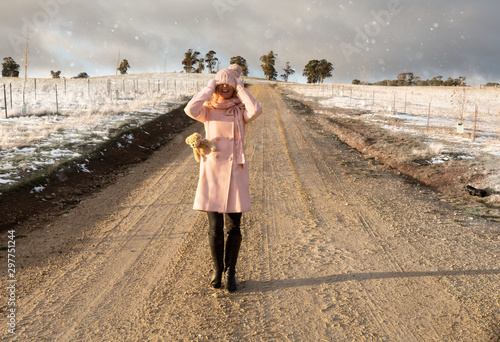 Happy go lucky woman walking down dirt road in light snow fall photo