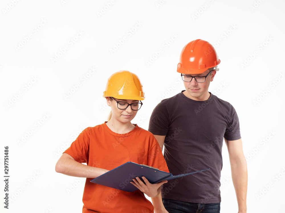 Emotional, young - a man with a woman foreman in yellow helmets with glasses and a folder in his hands on a white background Emotional, young - a man with a woman foreman in yellow helmets with glasses and a folder in his hands on a white background