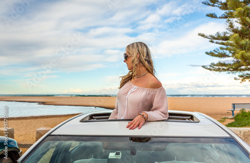 Road trip to beach. Carefree woman in sunroof with views © Leah-Anne Thompson