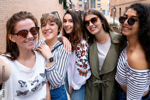 Five female friends seated on stairs in the street taking a selfie