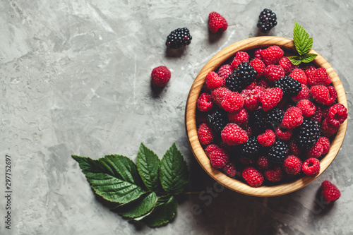 raspberries and blackberries in wood bowl on gray table, vintage