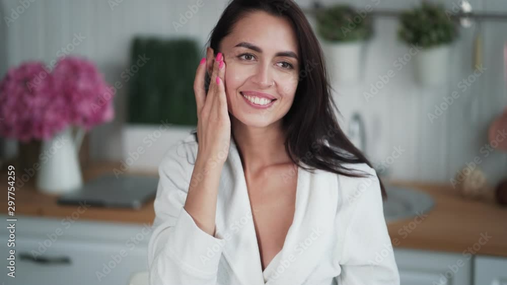 Portrait of young woman applies moisturizing serum to face and does face massage Portrait of young woman applies moisturizing serum to face and does face massage