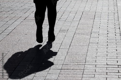 Silhouette of fat woman walking down the street, black shadow on pavement. Thick legs, concept of overweight, diet, loneliness, dramatic life story