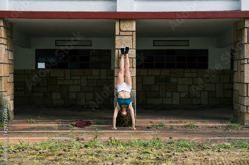 Fit young woman doing handstand. Outdoor urban fitness workout.