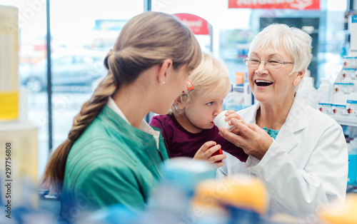 Friendly pharmacist  mother and child having fun in pharmacy