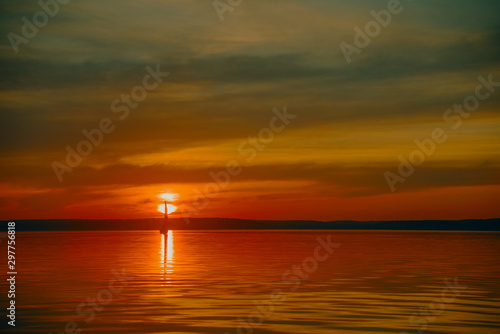 Sailing boat floats on the lake at sunset. © Виталий Волосевич