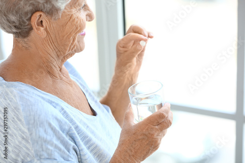 Elderly woman taking medicine at home