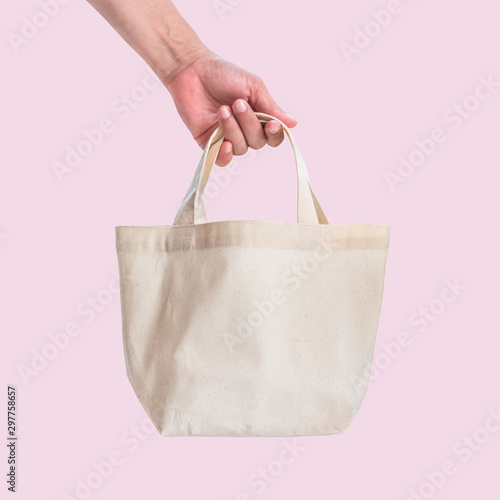 Tote bag canvas white cotton fabric cloth for eco shoulder shopping sack mockup blank template isolated on pink background (clipping path) with woman’s hand handling handle straps