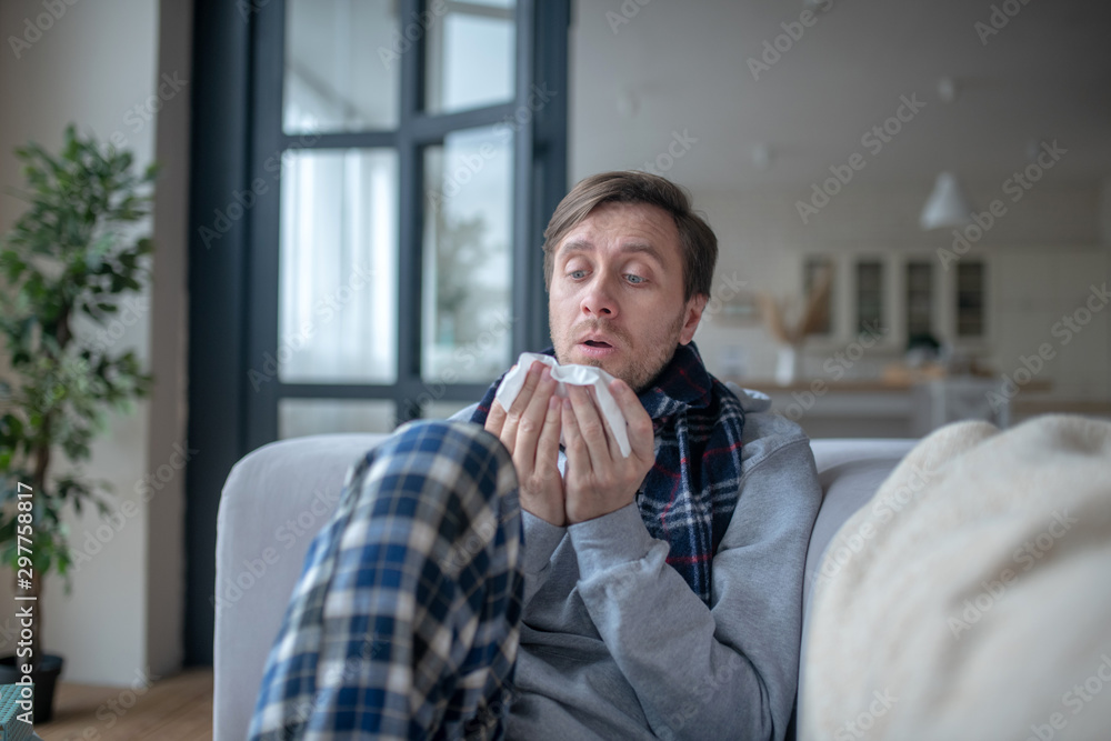 Businessman spending day at home wearing scarf while having flu Businessman spending day at home wearing scarf while having flu