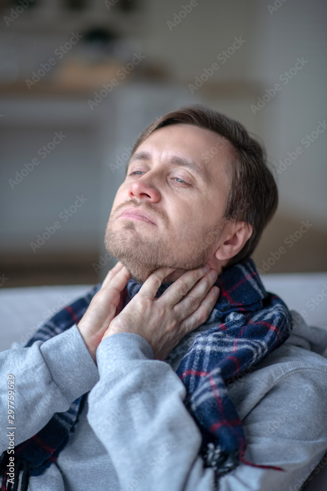Sick man wearing scarf while feeling sick and cold Sick man wearing scarf while feeling sick and cold